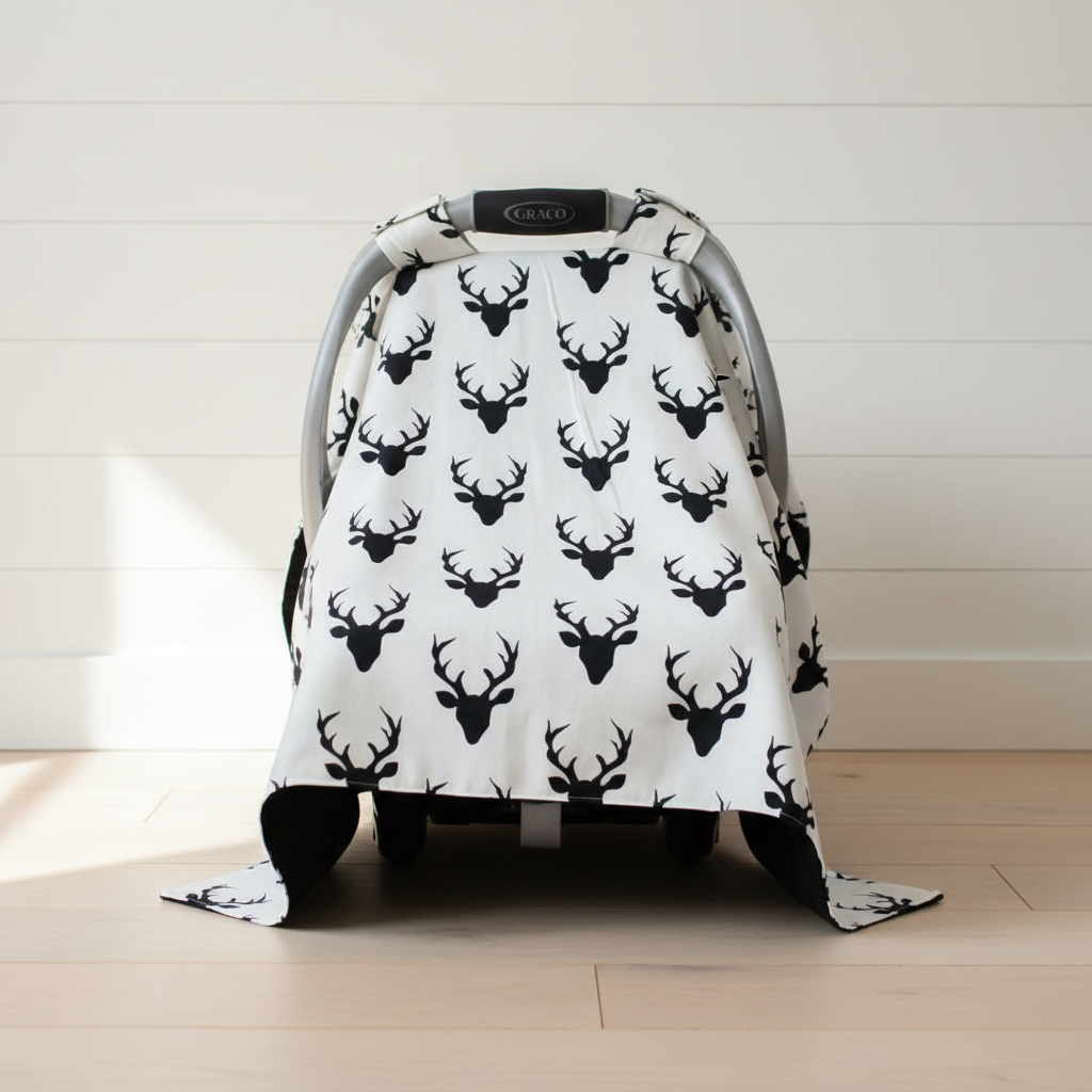 Buck Woodland Carseat Tent against white shiplap wall — black buck print with black cotton underside visible, handmade in the USA