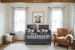 Zoomed in view of farmhouse nursery with navy arrow and cow print bedding